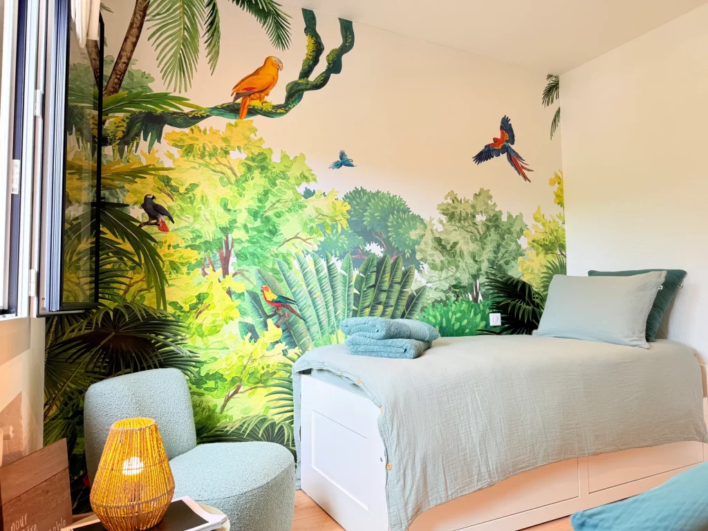 Chambre d'enfant à la Villa Plen Souleù à Cabris avec papier peint jungle, lit simple et fauteuil bouclé.