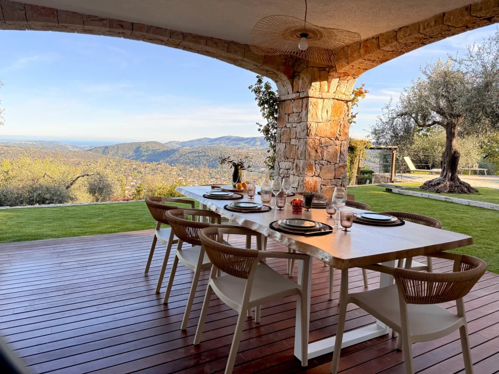 Terrasse couverte en pierre de la Villa Plen Souleù à Cabris, avec table dressée pour 8 personnes et vue panoramique sur la baie de Cannes.