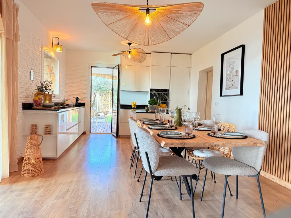 Salle à manger et cuisine ouverte lumineuses de la Villa Plen Souleù à Cabris, avec table dressée pour 8 personnes.