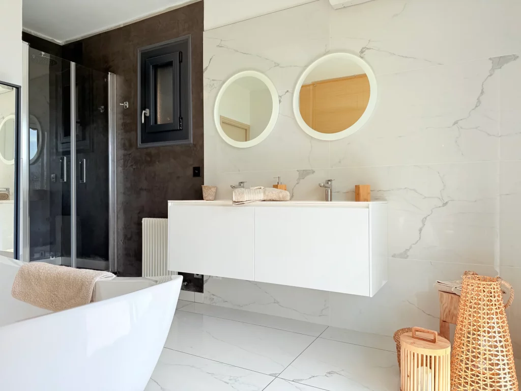 Salle de bain de luxe moderne avec double vasque et miroirs ronds rétroéclairés à la Villa Plen Souleù, Cabris.