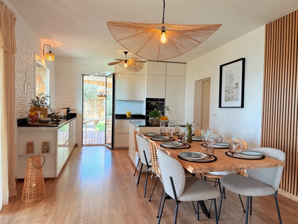Salle à manger et cuisine ouverte de la Villa Plen Souleù à Cabris, avec table dressée pour 8 personnes et vue sur le jardin.