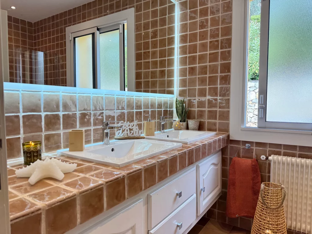 Salle de bain double vasque provençale à la Villa Plen Souleù, Cabris, avec carreaux de terre cuite et vue extérieure.