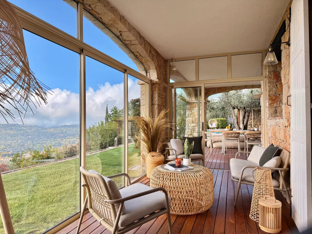Salon de terrasse vitré de la Villa Plen Souleù à Cabris, avec vue panoramique sur la baie de Cannes.